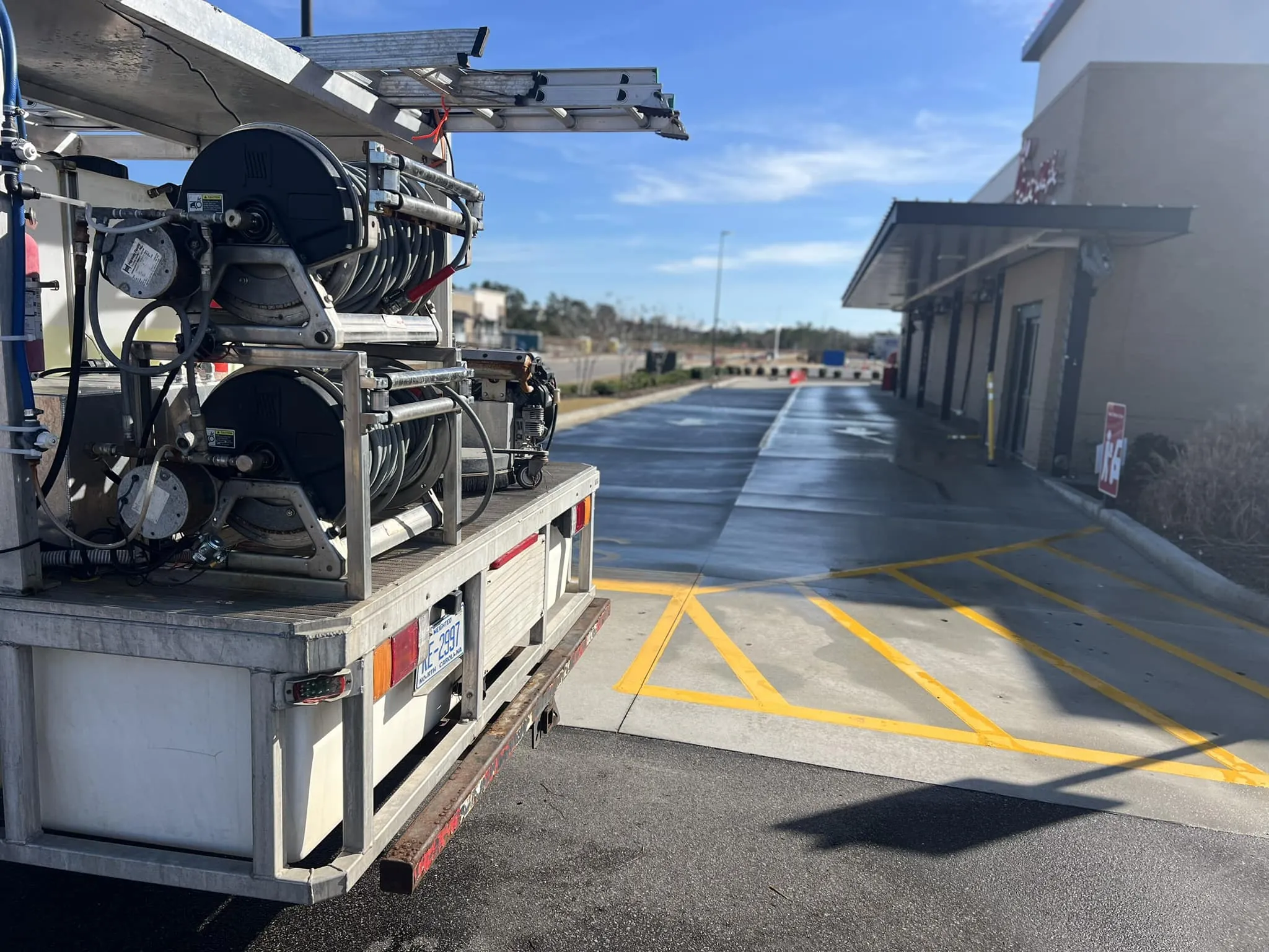 power-washing-truck-rear-equipment-view-at-residential-driveway-near-landscaping-wilmington-nc pressure washing company in Calabash, NC